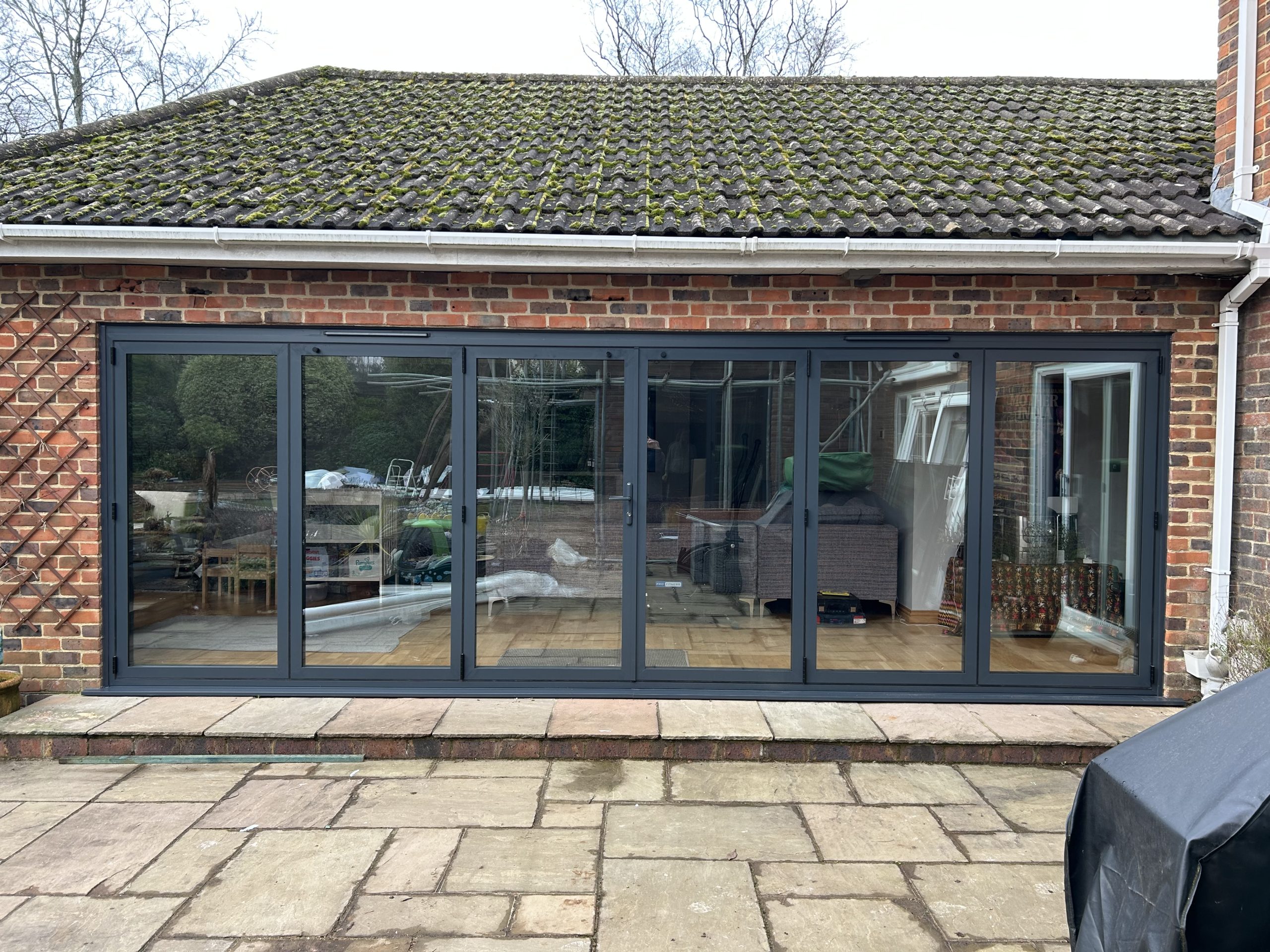Black-framed six-panel bi-fold door, brick extension
