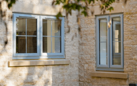 White casement windows on a stone cottage wall