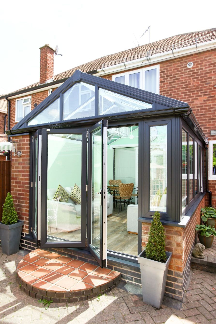 Anthracite gable-end conservatory with aluminium bi-fold doors open