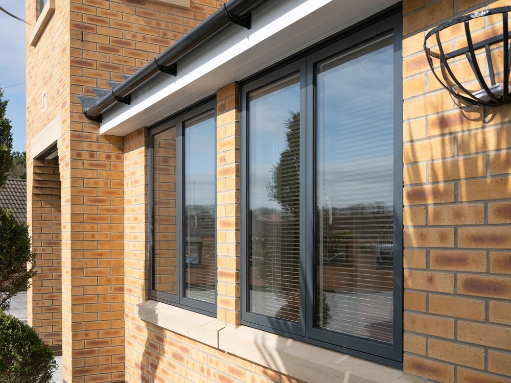 Anthracite grey Sheerline aluminium windows on a buff brick house