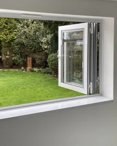 White aluminium bi-folding window folded open onto a garden